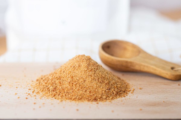 Sucre de coco sur une planche à découper avec une cuillère en bois