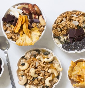 Bols de granola enrichi en probiotiques avec des morceaux de chocolat, des copeaux de noix de coco, des graines de tournesol et des noix de cajou