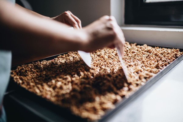 Femme préparant du granola maison sur une plaque de cuisson