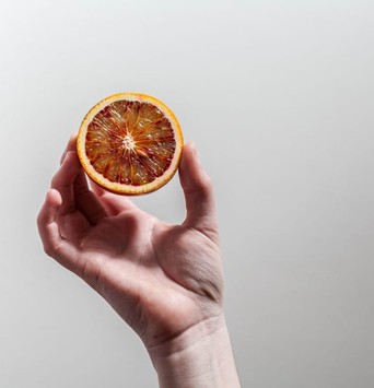 Moitiée d'orange tenue par une main, comme exemple d'aliment bénéfique pour le microbiote intestinal