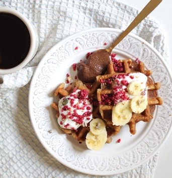 Gaufre végane maison avec topping de banane, servie dans une assiette accompagnée d'un mug