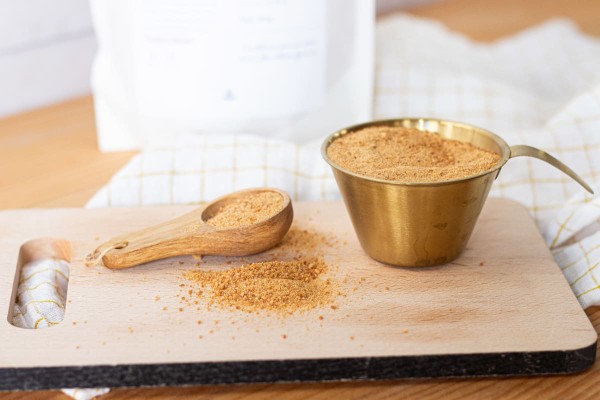 Pot de sucre de coco avec une cuillère en bois sur une planche à découper