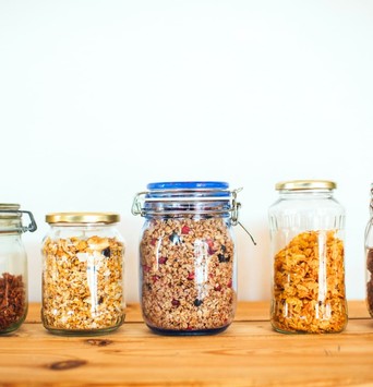 Jarres de muesli, granola et flocons d'avoine nature sur une table