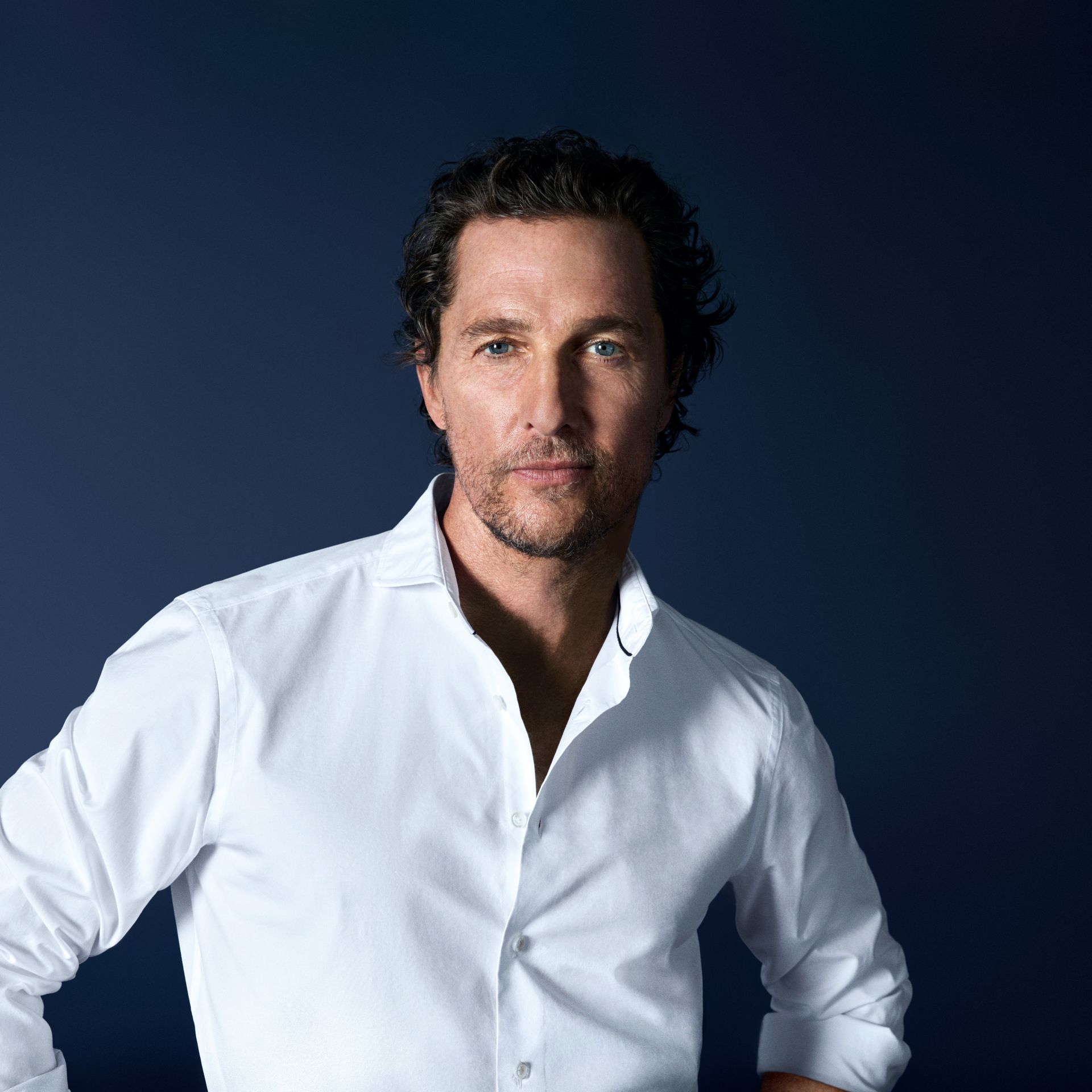 Matthew McConaughey trägt ein weißes OLYMP-Hemd vor dunklem Hintergrund.