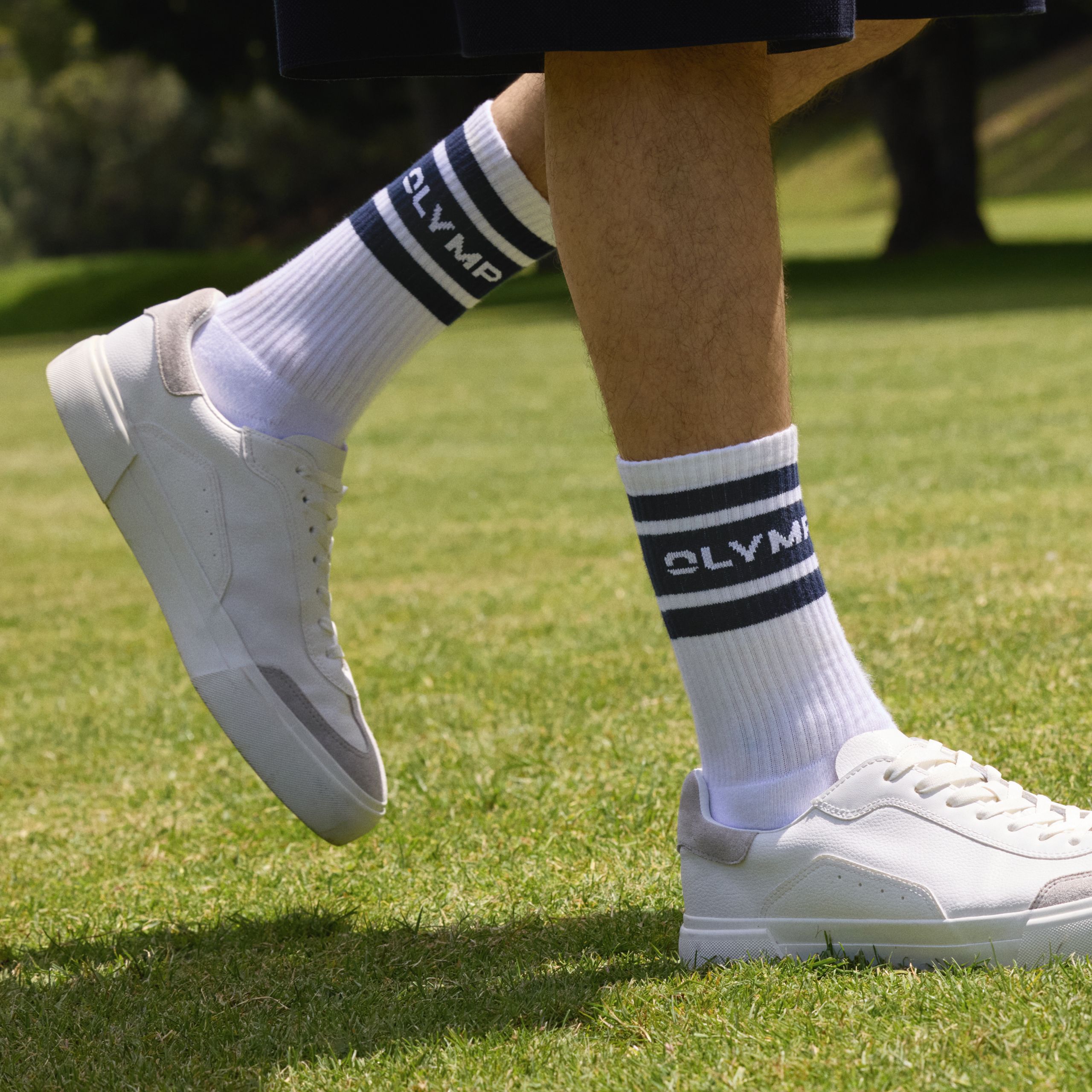 Detailaufnahme von weißen OLYMP Tennissocken mit Streifen und Logo.