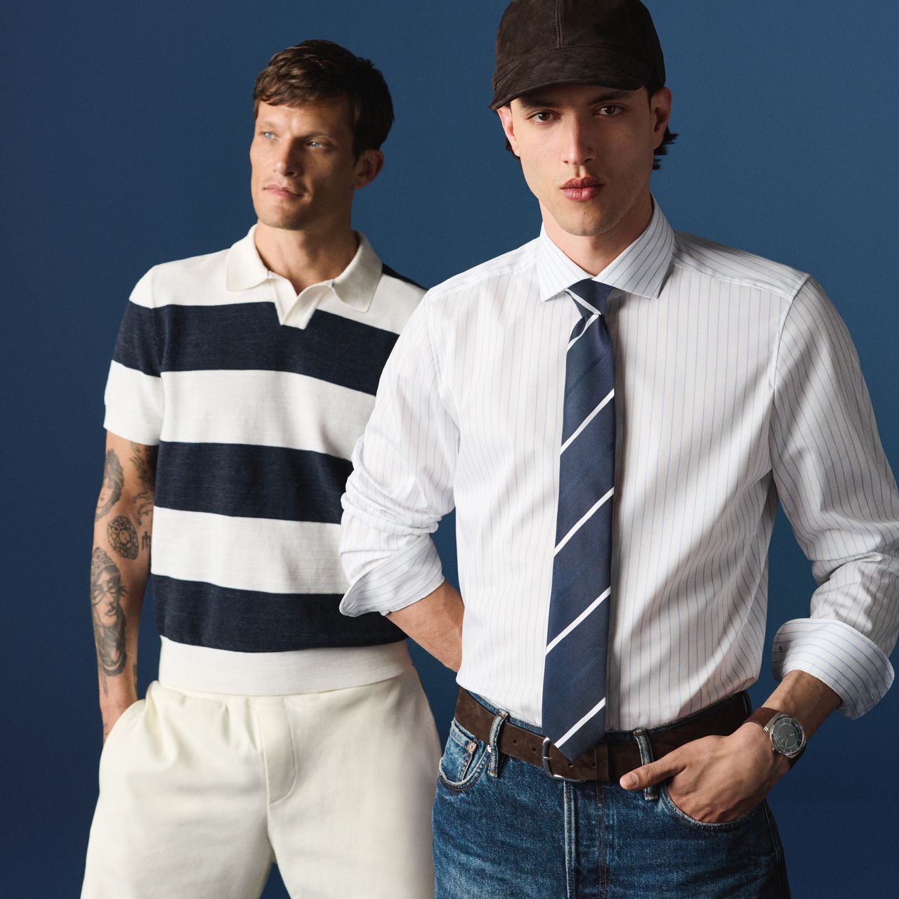 Zwei Models tragen die OLYMP Frühjahr-Sommer Kollektion. Das vordere Model trägt ein helles, fein gestreiftes Businesshemd mit Krawatte. Dahinter steht ein weiteres Model in einem kurzärmeligen Poloshirt mit breiten Streifen in Dunkelblau und Weiß.