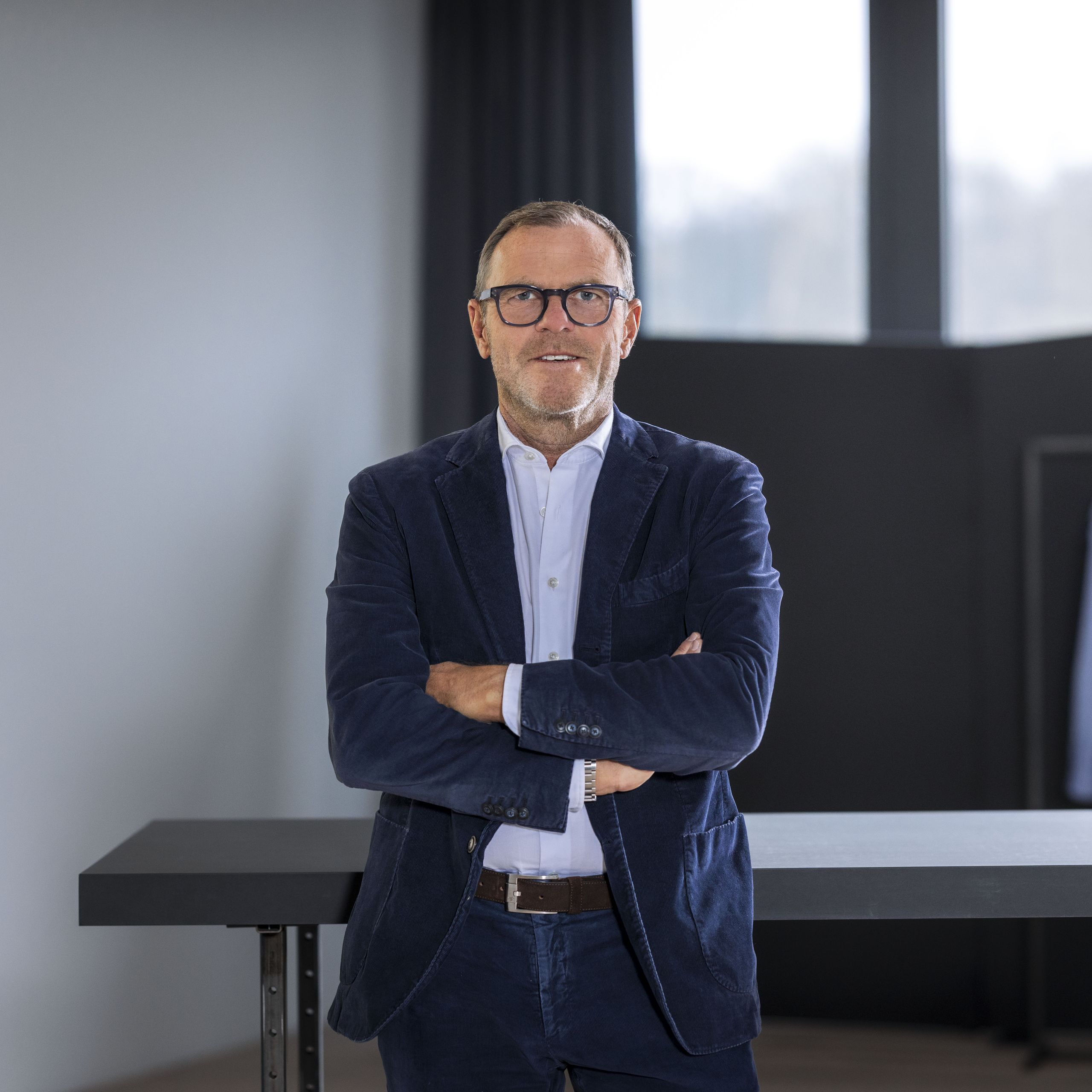 Mark Bezner, CEO/CFO und Inhaber von OLYMP, steht im Anzug in einem Showroom.