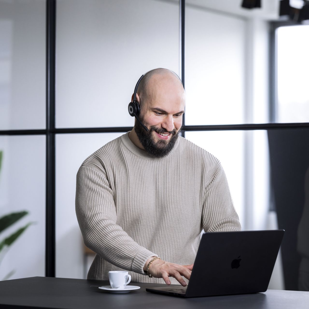 OLYMP Mitarbeiter sitzt in einem Büro vor einem Laptop. Er trägt ein Headset mit Mikrofon.