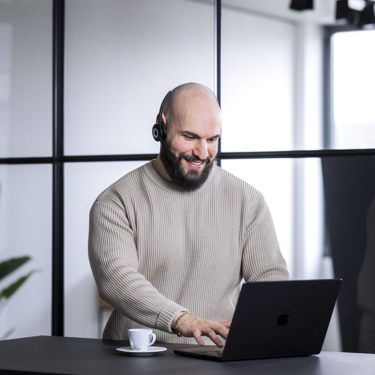OLYMP Mitarbeiter sitzt in einem Büro vor einem Laptop. Er trägt ein Headset mit Mikrofon.