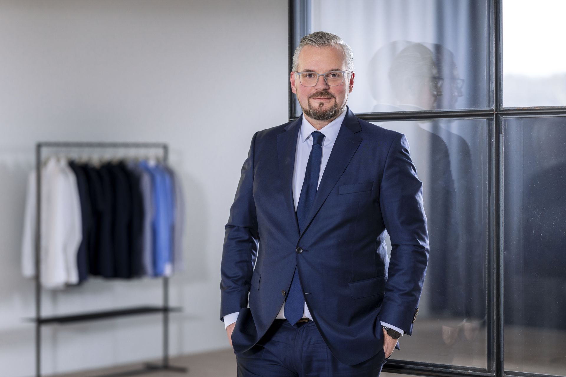 Johann Trischberger, COO von OLYMP, im blauen Anzug mit Krawatte in einem Showroom.