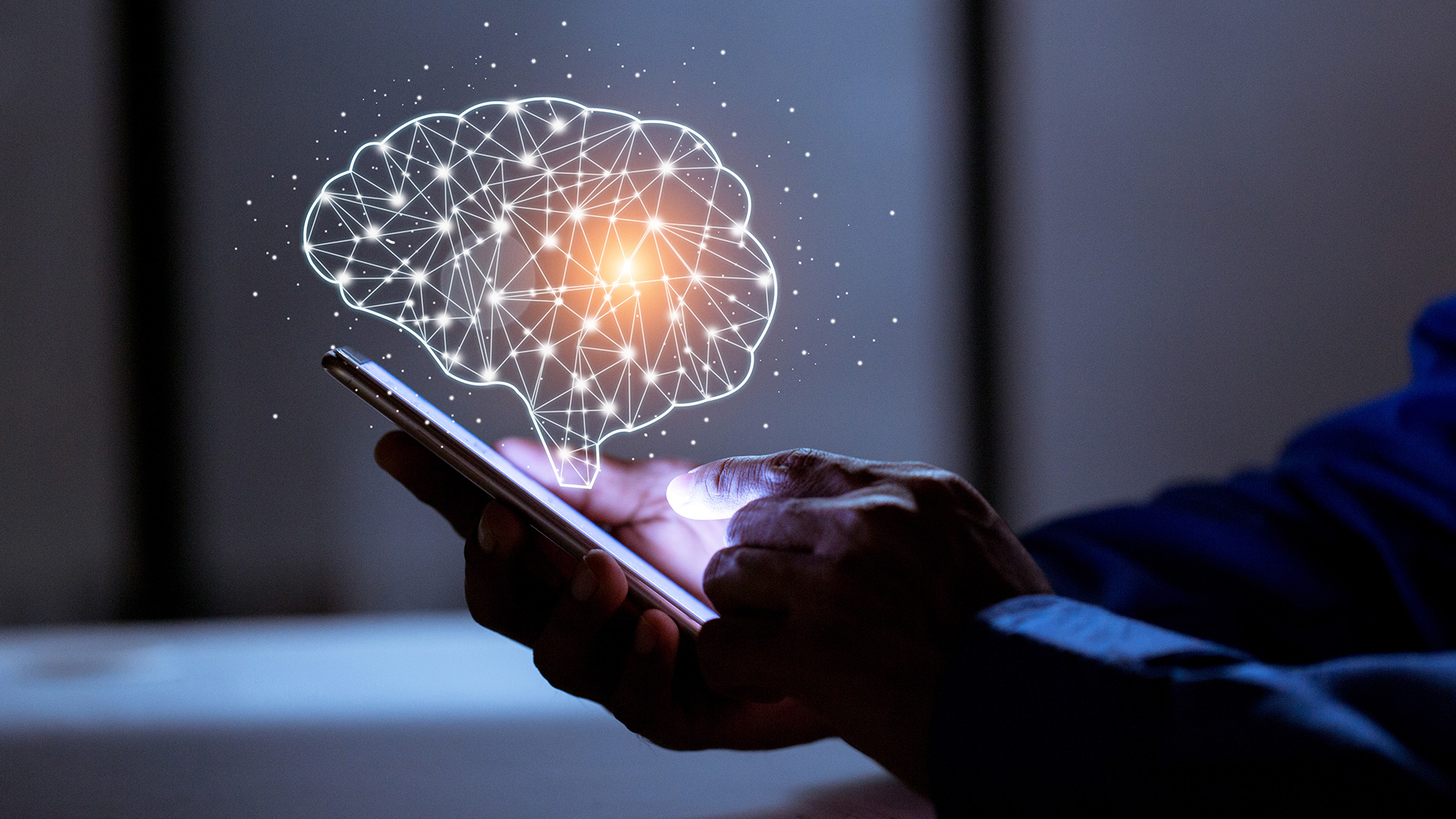 Eine Person hält ein Smartphone in der Hand, über dem eine leuchtende, digitale Gehirnprojektion zu sehen ist.