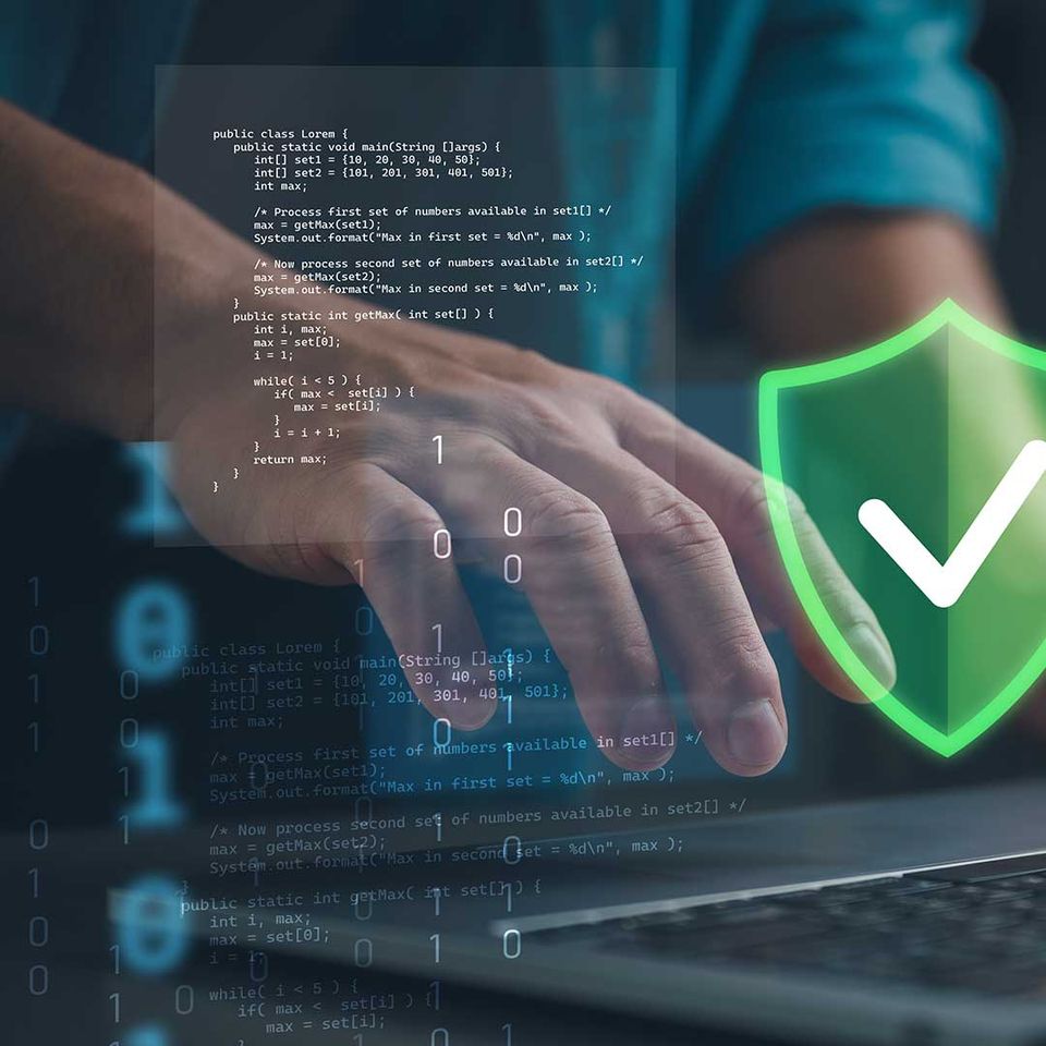 Hände an einem Laptop mit Programmiercode, darüber ein leuchtendes Schutzschild mit Häkchen als Symbol für sichere Daten und geschützte IT-Systeme.
