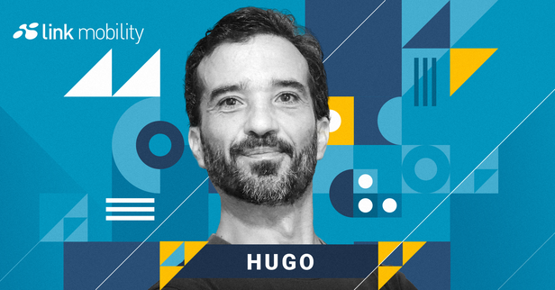 A man with a beard is smiling in front of a geometric, blue and yellow abstract background, with "Link Mobility" and "Hugo" text on the image.