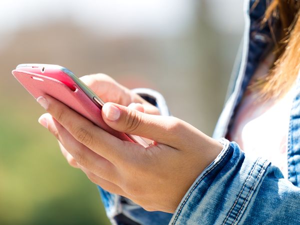 Person interacting with smartphone, representing real-time notifications and multichannel customer communication across SMS, email, push, and messaging apps.