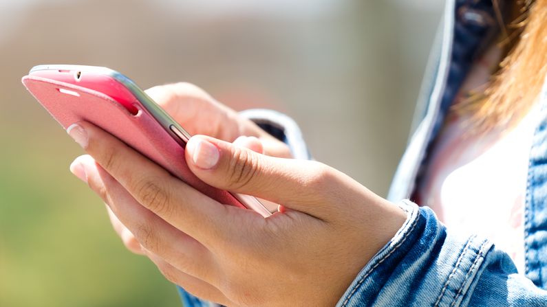 Person interacting with smartphone, representing real-time notifications and multichannel customer communication across SMS, email, push, and messaging apps.