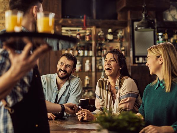 Group of guests enjoying drinks in a hotel or restaurant setting, illustrating guest satisfaction and engagement as highlighted in the WhatsApp Hospitality Ebook.
