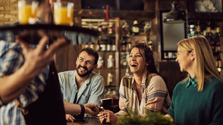 Group of guests enjoying drinks in a hotel or restaurant setting, illustrating guest satisfaction and engagement as highlighted in the WhatsApp Hospitality Ebook.