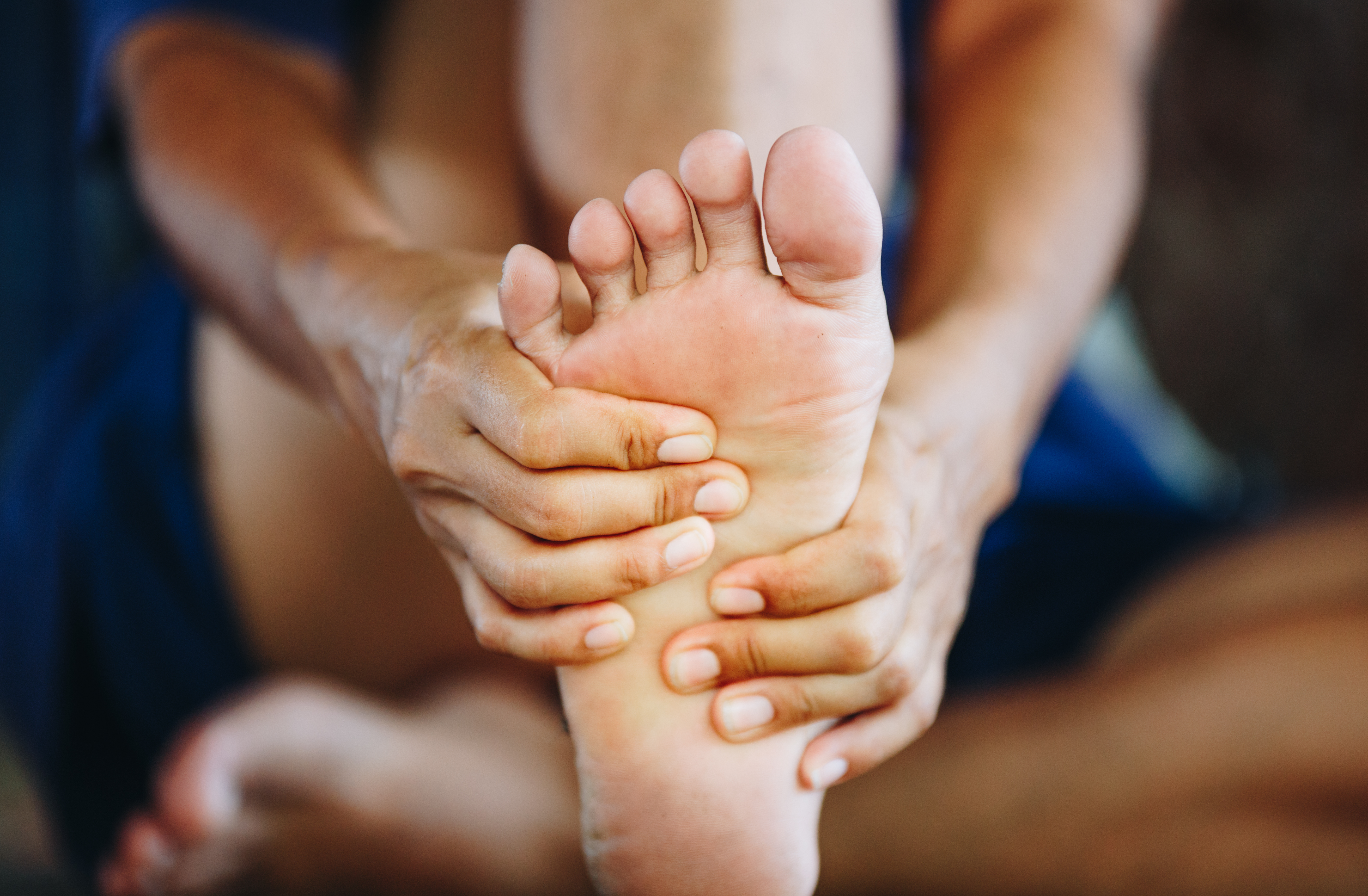 Sole of a foot being held by two hands, indicating pain