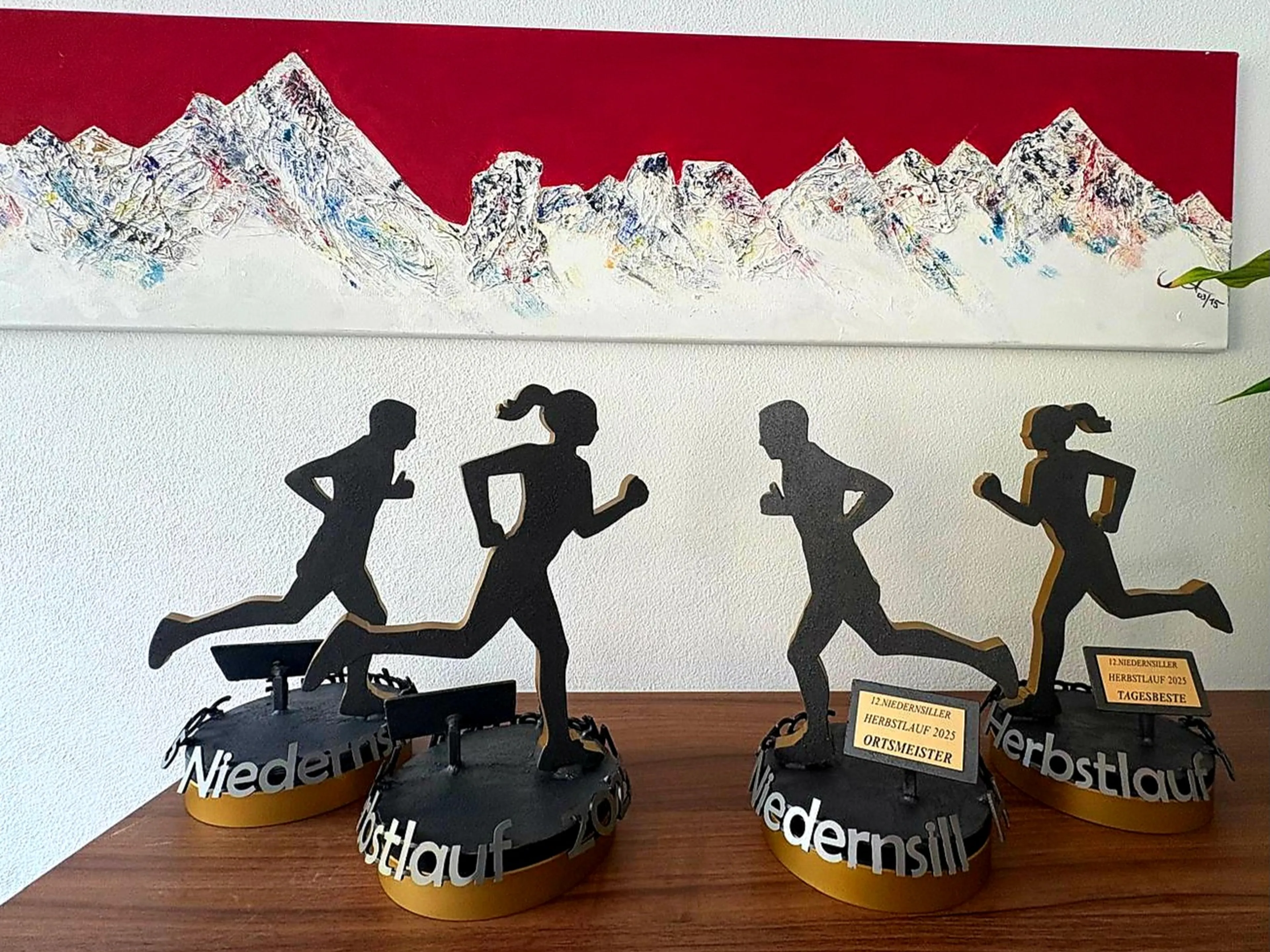 Fertige Pokale für den Niedernsiller Herbstlauf 2025; 2 männliche und 2 weibliche Läufer aus Stahl, mit Farbe lackiert, auf einem runden, drehbaren Stahlsockel mit dem gelaserten Schild "Ortsmeisterin oder Tagesbeste bzw. Ortsmeister oder Tagesbester"