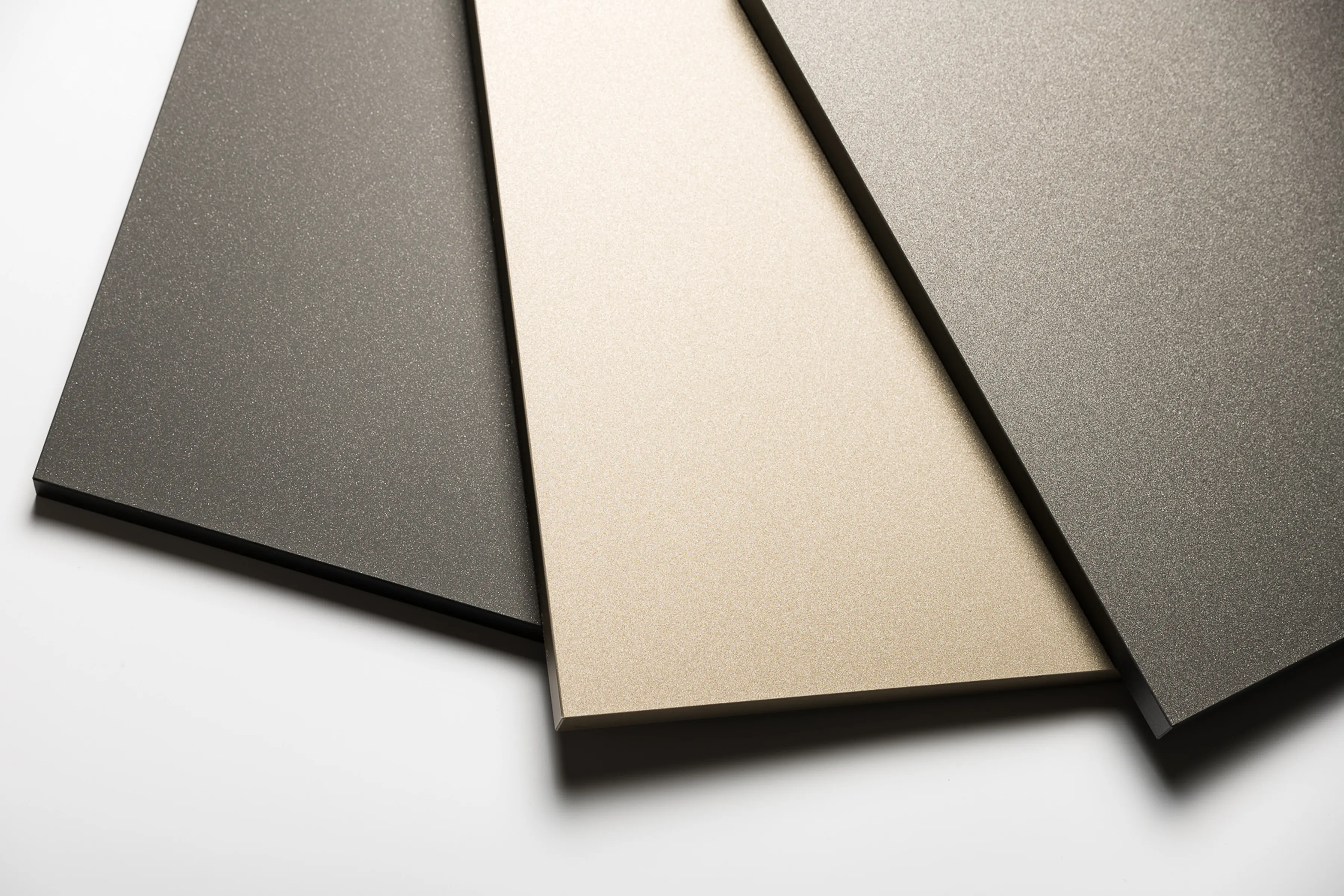 Four senosan® TOP M metallic panels in shades of gray and beige, arranged in a fanned-out pattern on a white background.