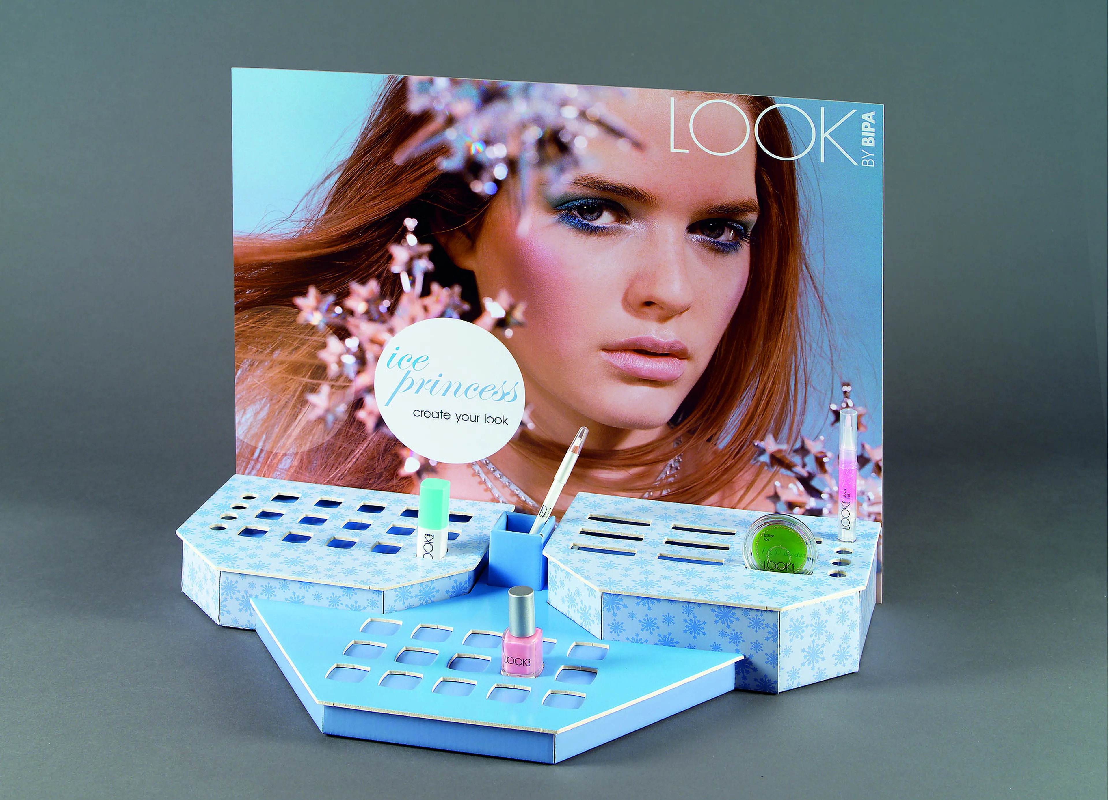 Cosmetics display with makeup items on a hexagonal stand. Background poster features a woman with long hair and the text "ice princess."