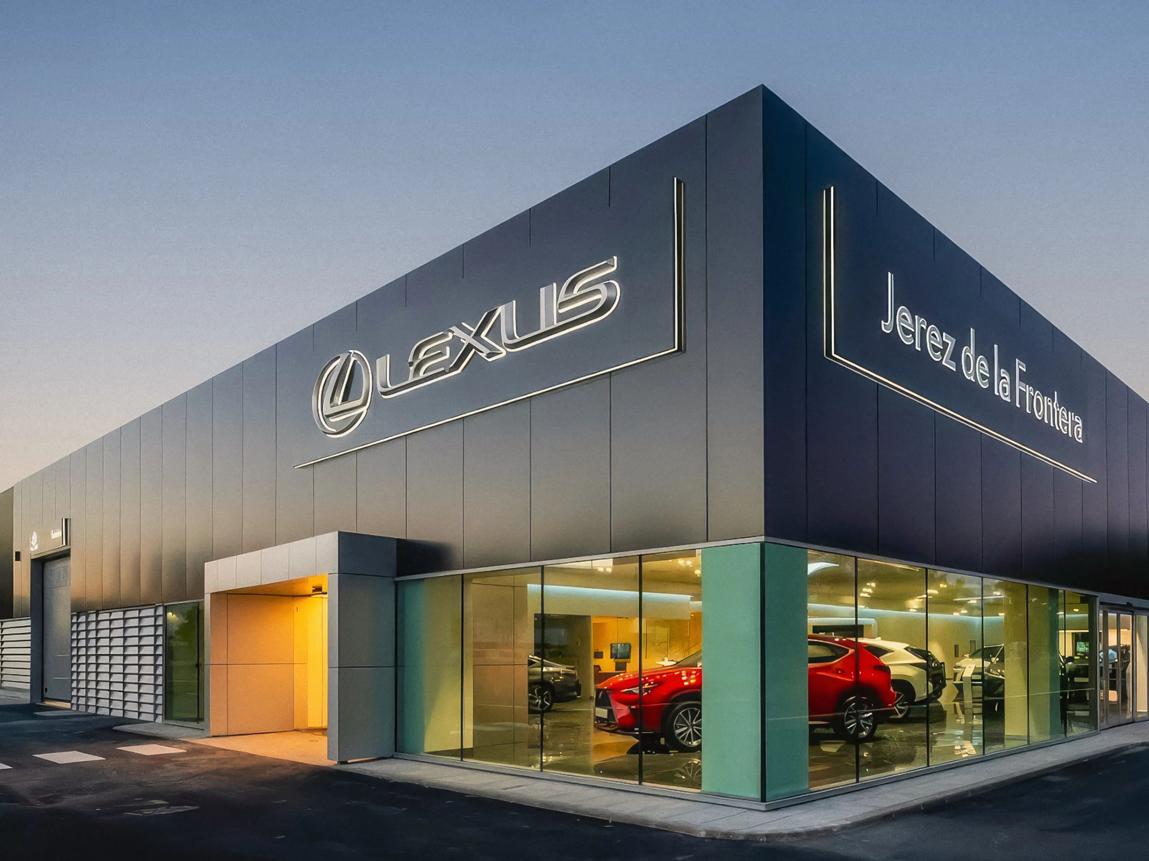 Modern Lexus dealership in Jerez de la Frontera at dusk, with sleek glass windows showcasing new cars inside.
