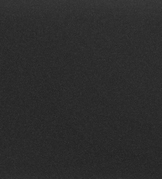 Dark textured surface with a subtle speckled pattern, resembling fine black sand against a backdrop.