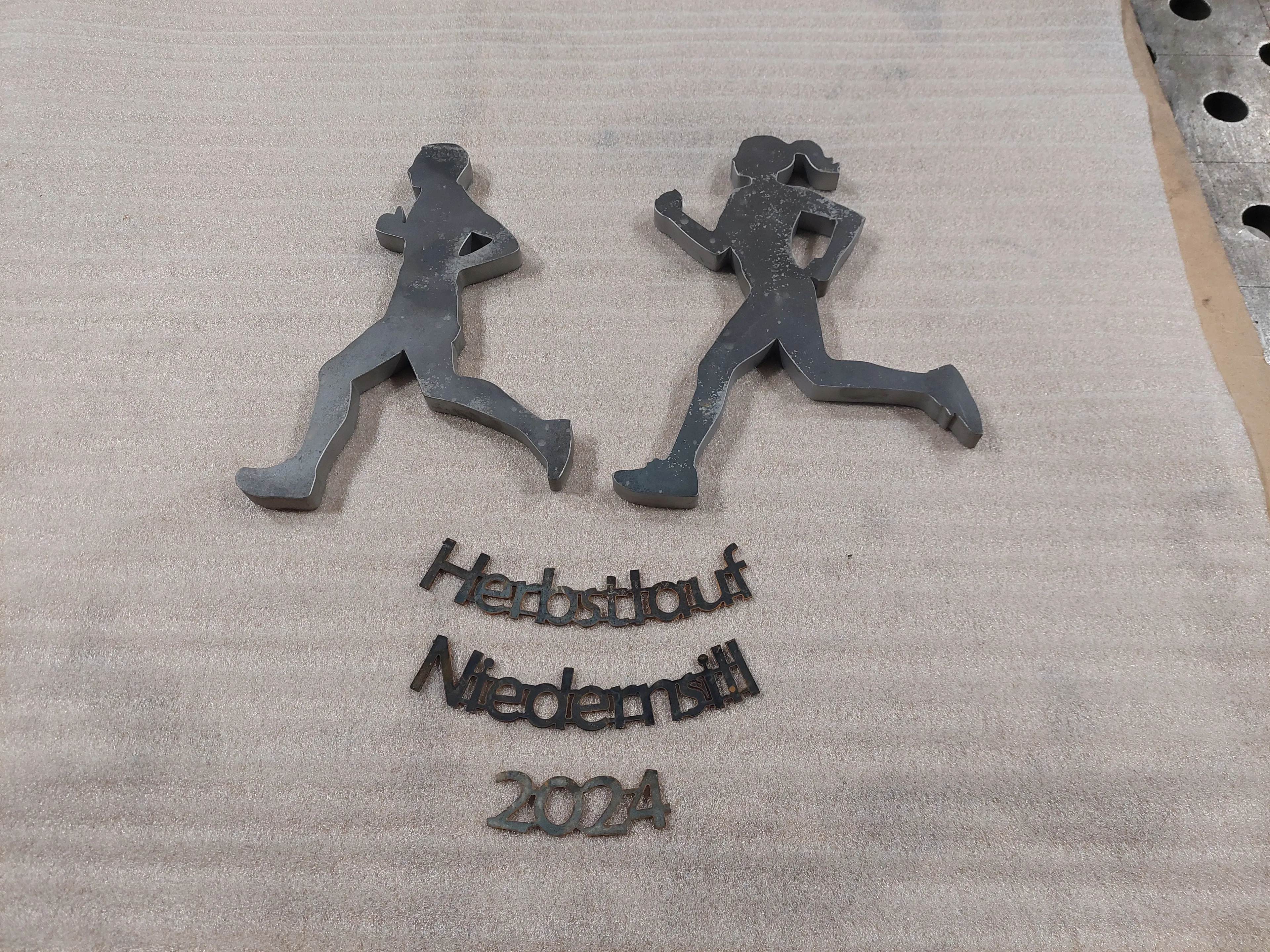 Stahlfiguren und Schrift für Pokale für den Niedernsiller Herbstlauf 2024, mit der Wasserstrahlschneidanlage von SENO Spezialmaschinen ausgeschnitten