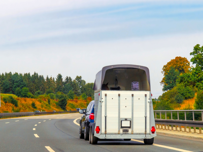 A car towing a trailer on a highway, illustrating trailer structure and fastening points assembled with customized blind rivets for strength and durability.