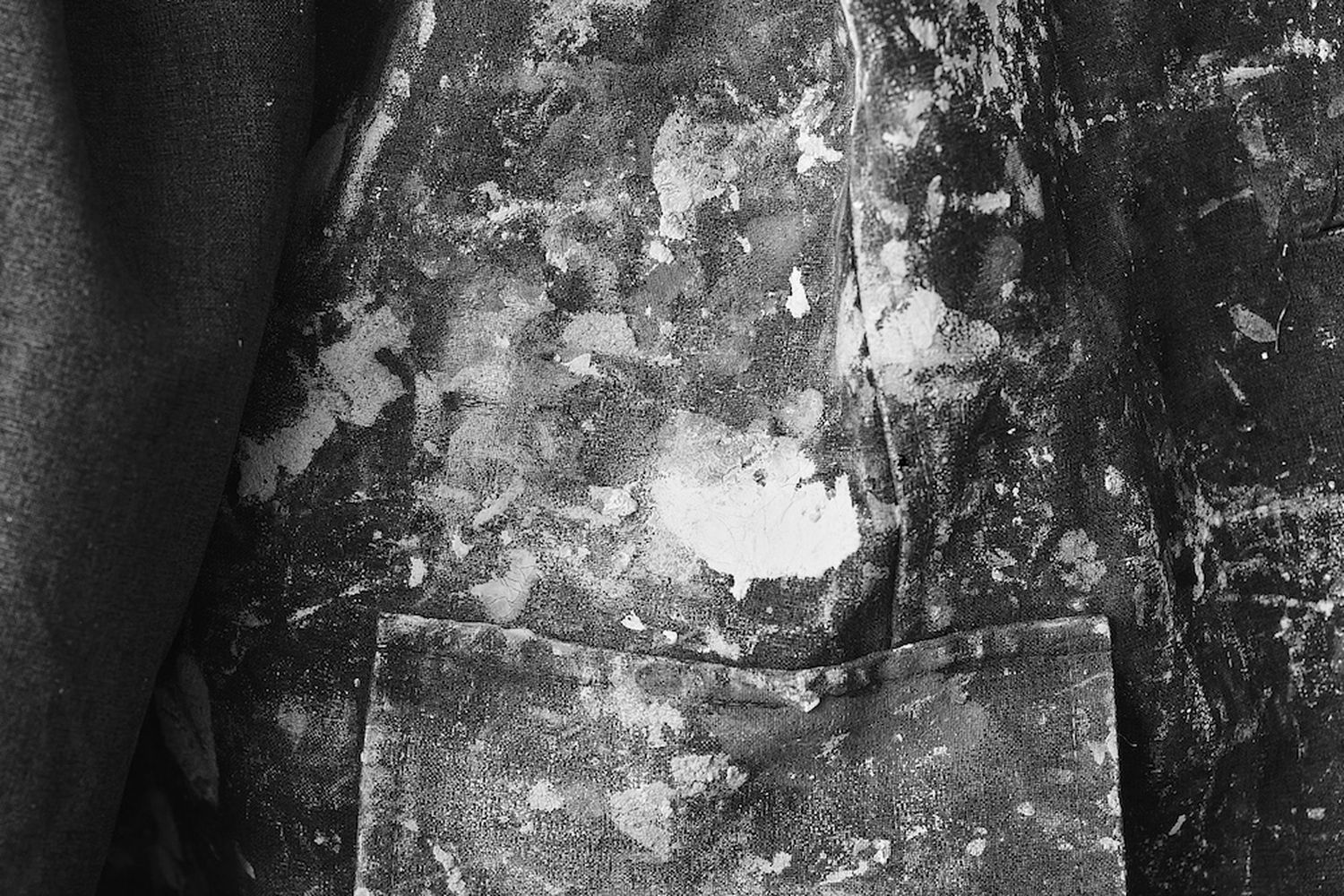A close-up of a dirty, wrinkled jacket with a white patch on the left side. [G]
