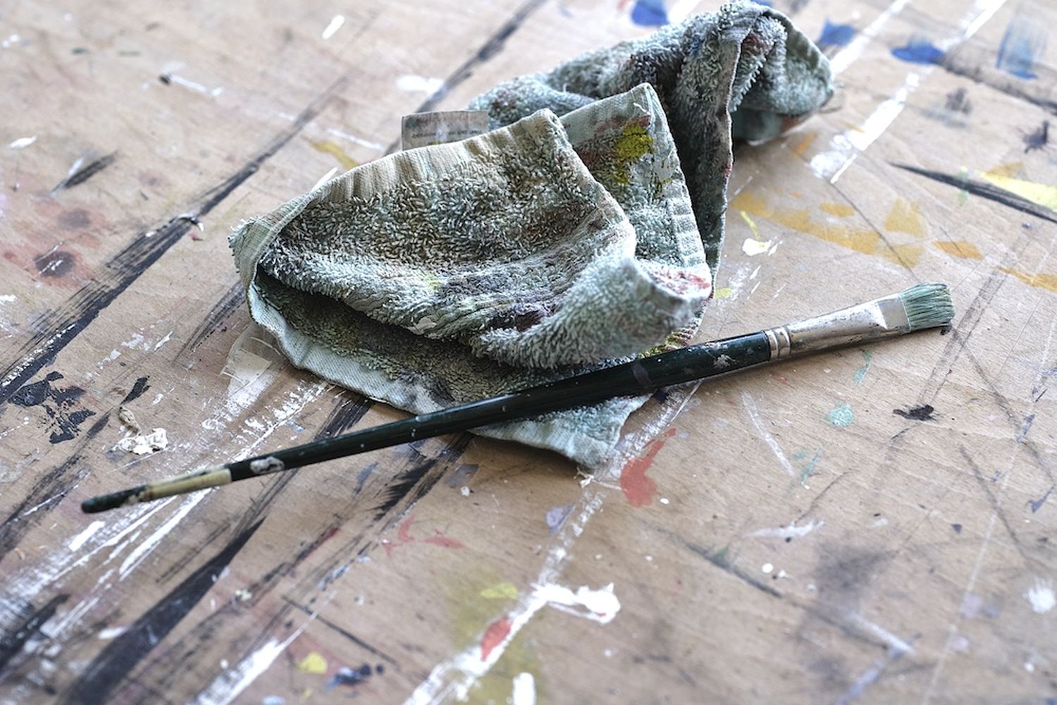 A canvas with a paintbrush and a cloth on a table. [G]