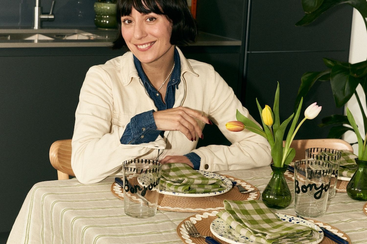 A woman sitting at a kitchen table with a green and white striped table cloth.
