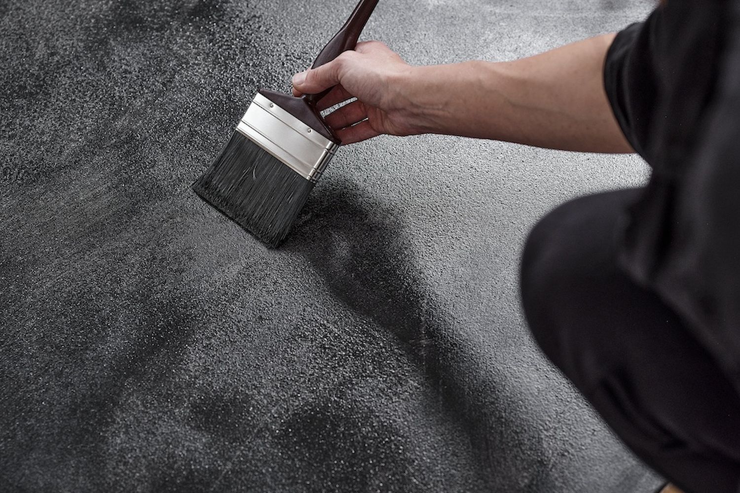 A person is painting a black surface with a brush. [G]