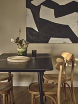 "Elegant dining area with modern abstract art, wooden chairs and stylish decor in Way of Life luxury apartment rentals featuring co-working spaces." [G]