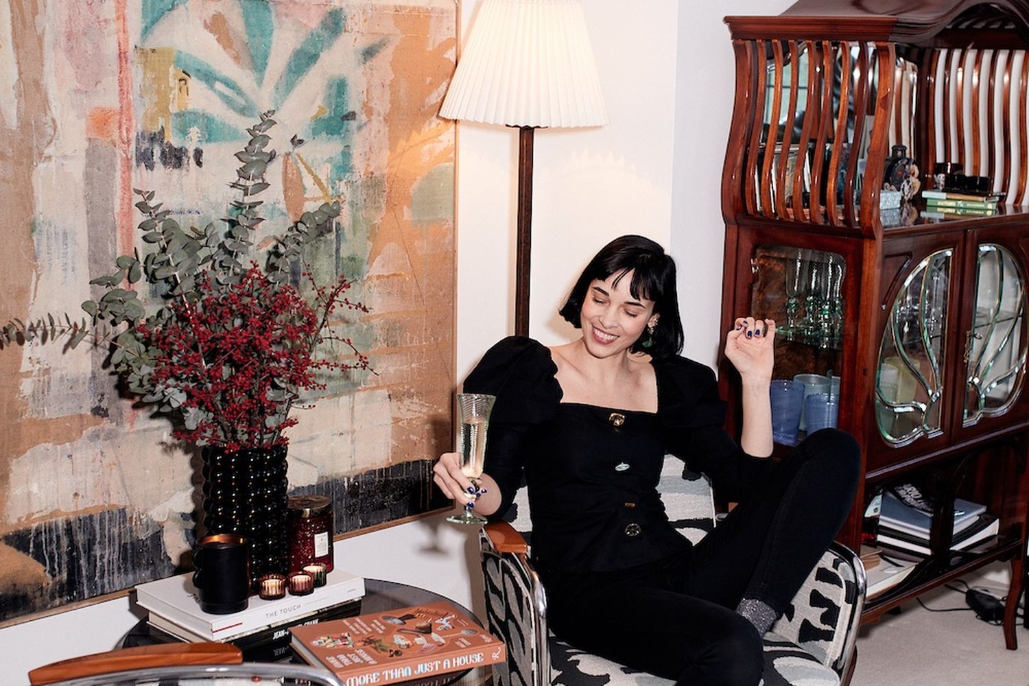 A woman is holding a champagne flute sitting in a black and white chair.