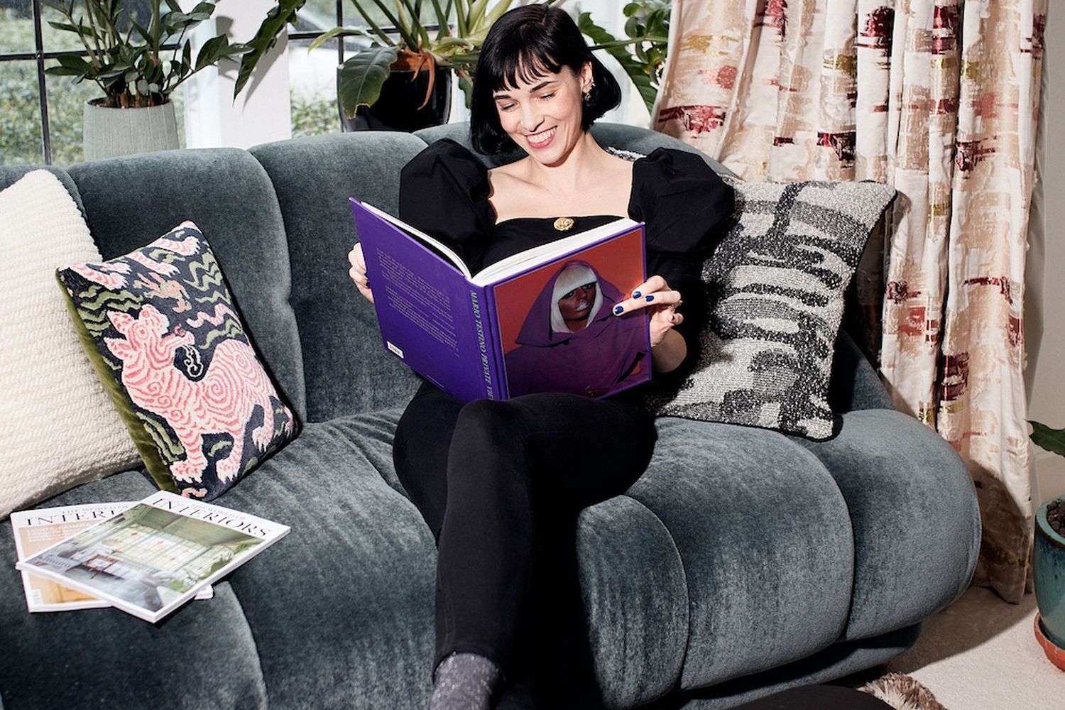 A woman sits on the sofa reading a book.