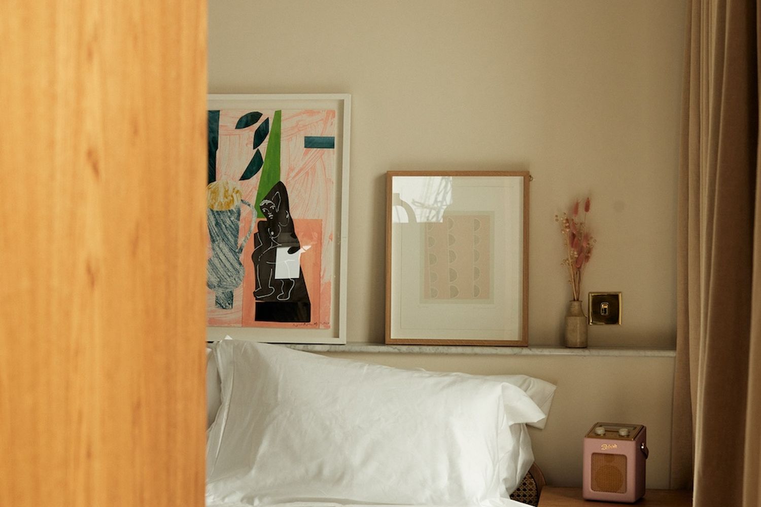 A bedroom with a bed, a dresser, a vase with flowers, and a clock. [G]