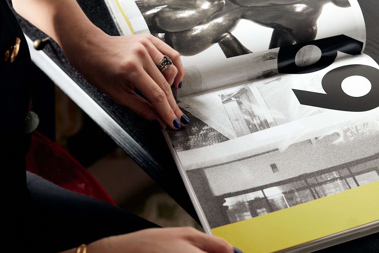 A woman is looking at a book that features a sculpture of a nude person.
