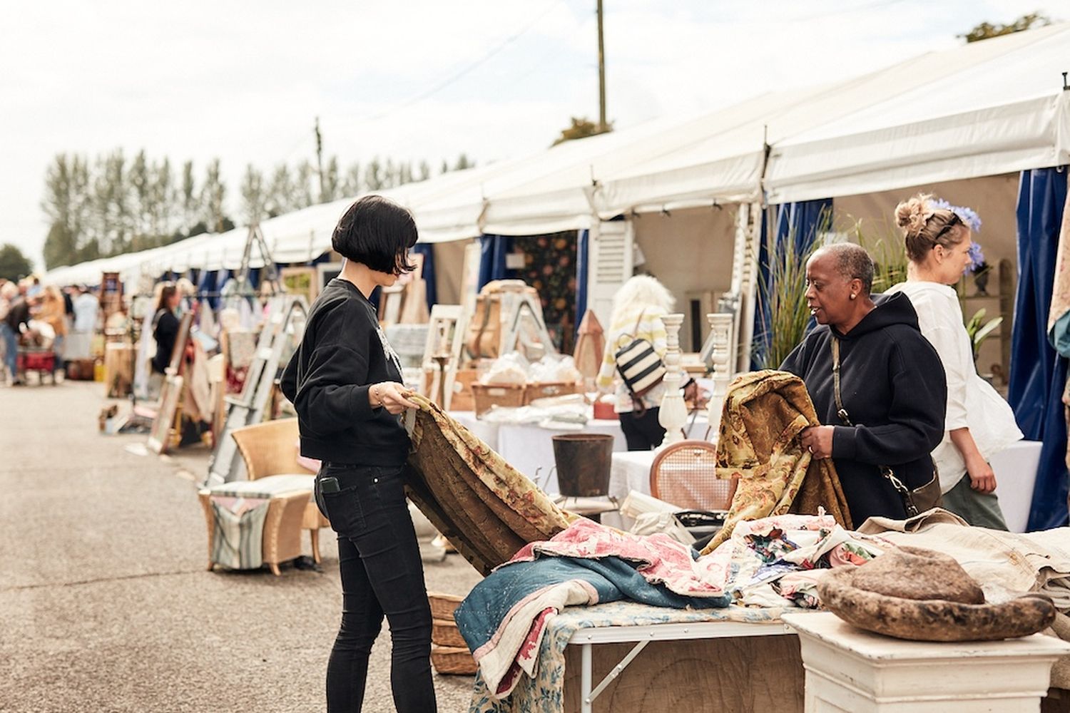 A woman holds a rug up to see what it looks like.