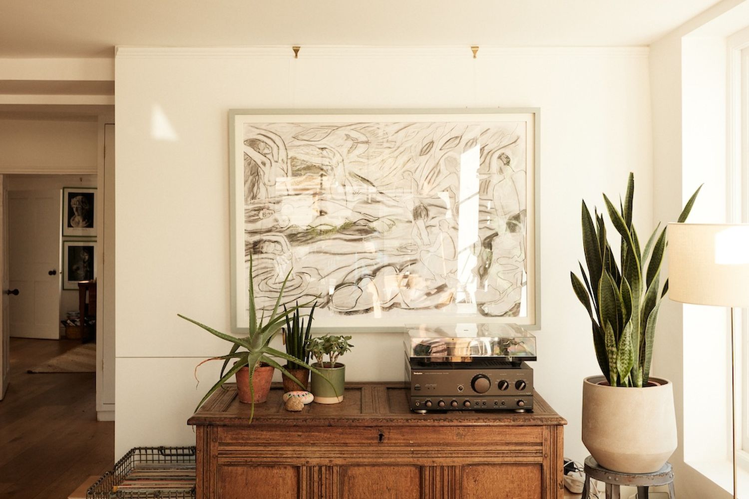 A vintage radio on a wooden cabinet, with a potted plant and a vase of flowers on the table. [G]