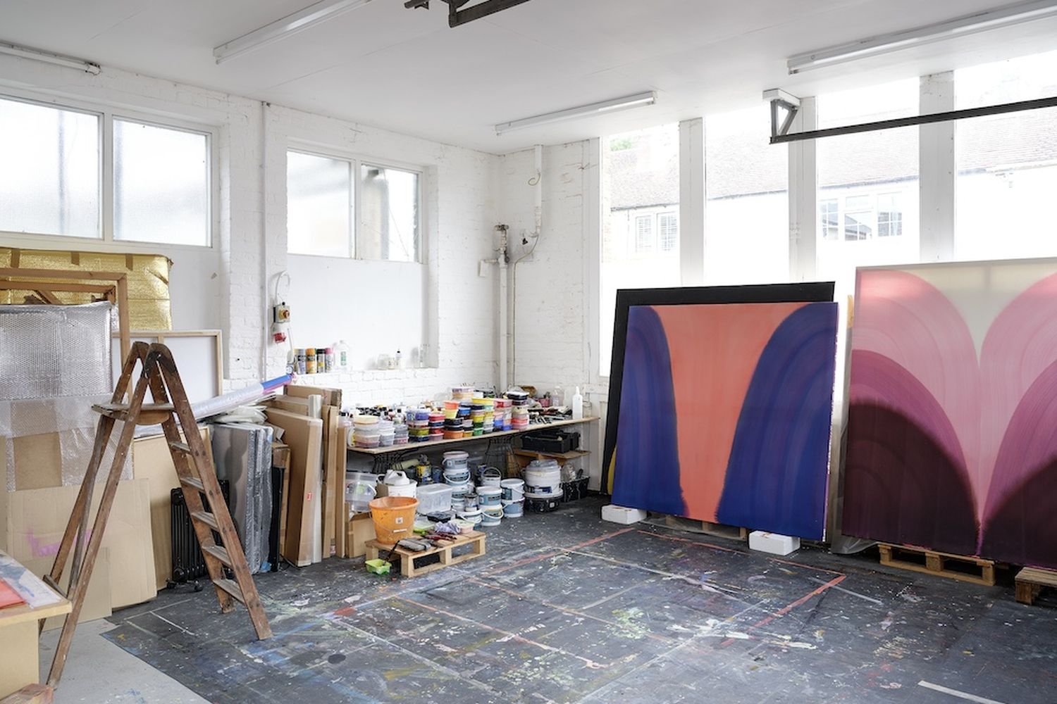 alt text: A room filled with art supplies and a large painting. [G]