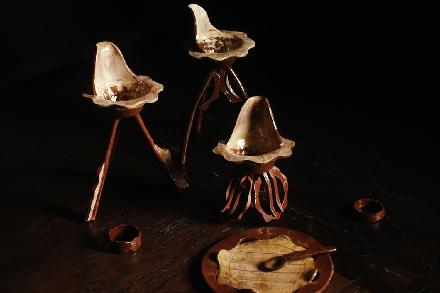 Ceramic brown glazed selection including three candle holders with two small candle holders or bowls, and a plate with a spoon.