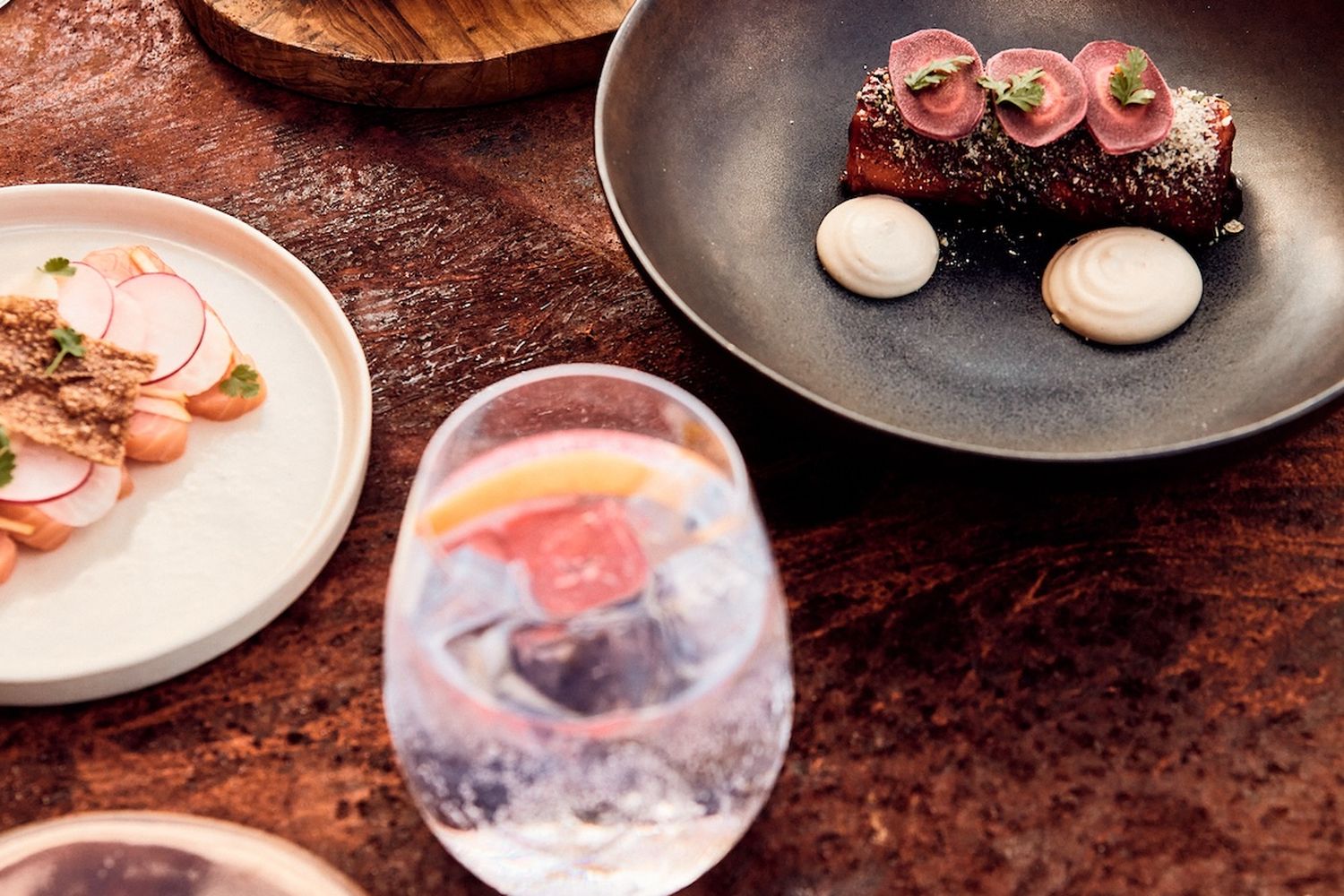 A restaurant scene with a variety of dishes on a wooden table. [G]
