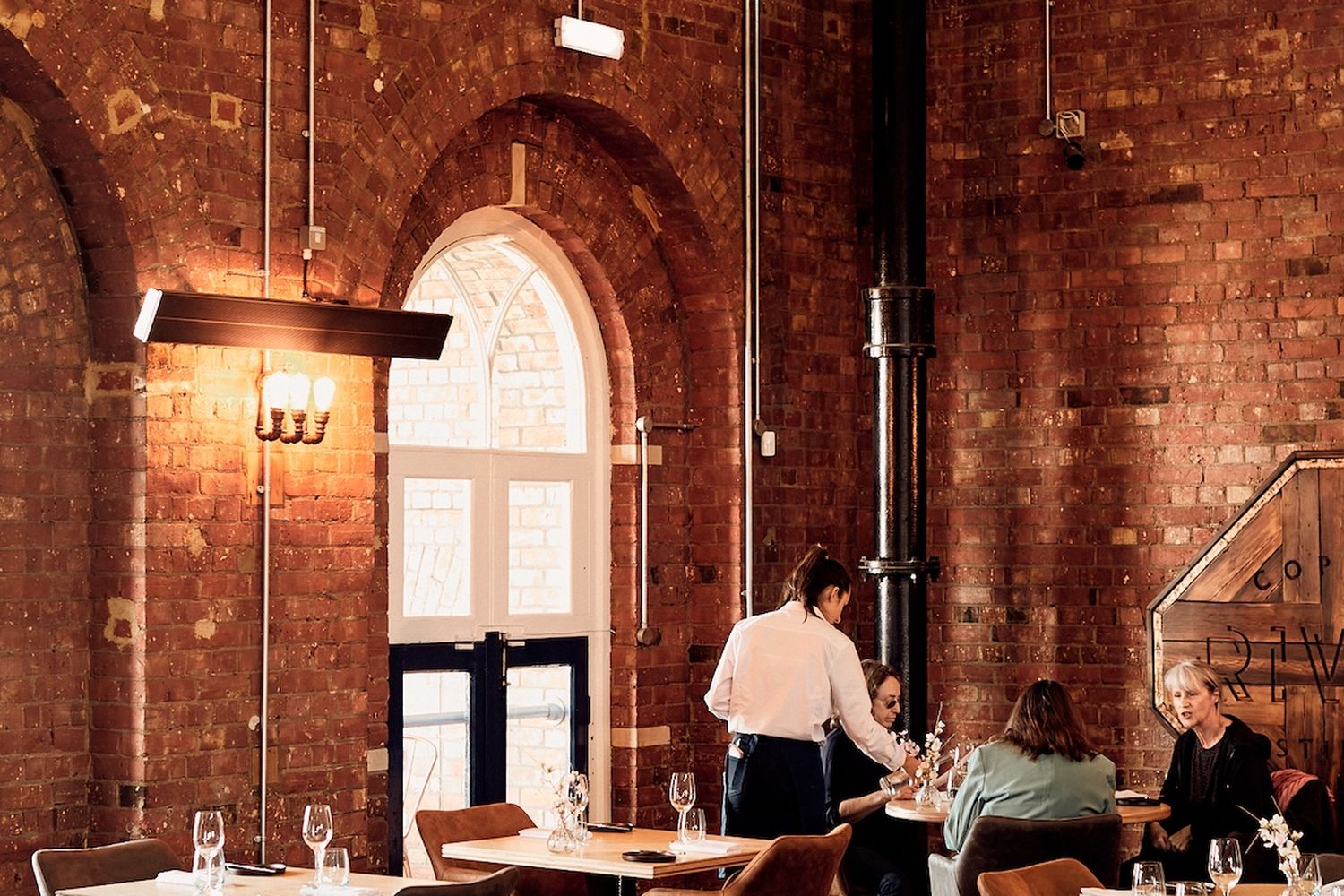 A restaurant with rustic brick walls and arched windows. [G]