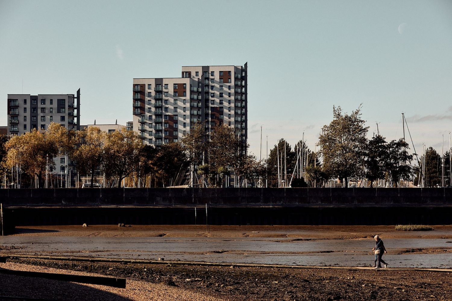 A river with boats and a person walking along it. [G]