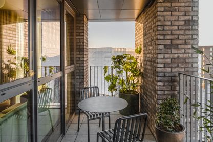 "Stylish balcony with table and chairs overlooking water view at Way of Life luxury apartment rentals, offering secure living." [G]