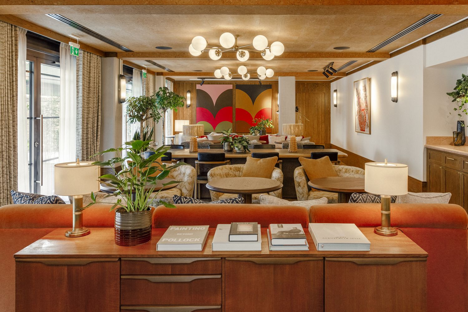 A cozy living room with a wooden desk, a large plant, and a comfortable sofa. [G]