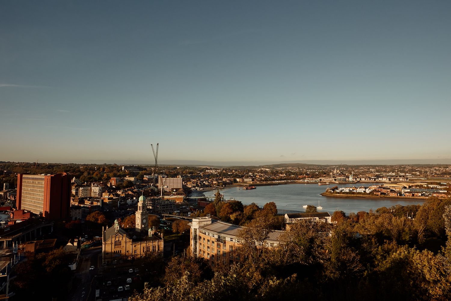 A maritime scene with a large body of water, boats, and a bridge. [G]