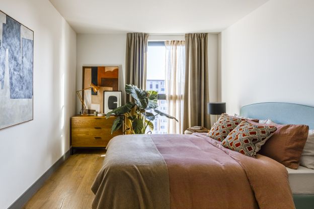 "Bright, stylish bedroom in Way of Life luxury apartment rentals featuring wooden floors, modern decor, and natural light through floor-to-ceiling windows." [G]