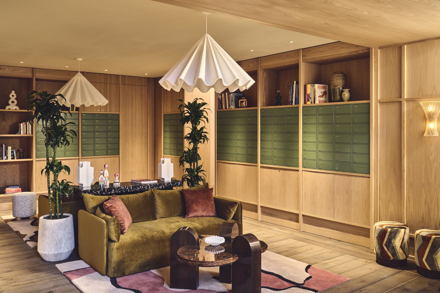 A cozy living room with a green sofa, wooden bookshelves, and a rug. [G]